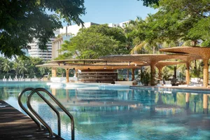Swimming pool surrounded by modern architecture, concrete deck, and lush greenery.