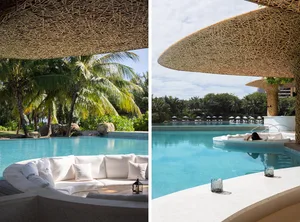 Luxurious outdoor area with wicker seating, concrete lounge, and a scenic poolside view surrounded by palm trees and natural 