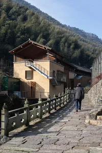 A modern architectural building made of wood, featuring a sloped roof and exterior stairs, situated in a natural setting with