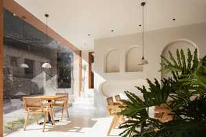 A modern cafe interior featuring mixed materials, with a focus on the light, airy ambiance created by the large windows and n