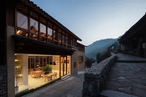 A modern restaurant with wooden exterior and large windows under a clear sky.