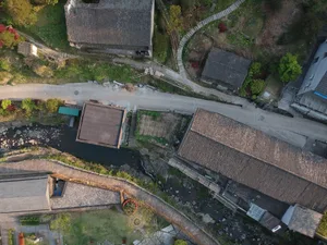 傳統村落的空拍視角，呈現磚造建築與狹窄道路，道路兩旁綠意環繞