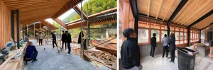 Construction workers assembling wooden beams in a spacious workshop with scaffolding and tools.