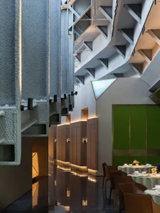 A spacious modern restaurant interior with concrete walls, stone floors, and sleek furniture.
