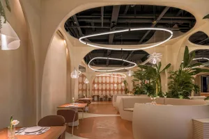 A modern restaurant interior with neutral-colored decor and arch-shaped ceiling lights.