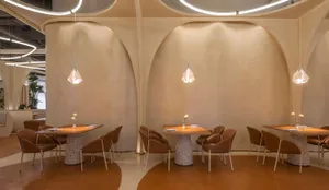Modern restaurant dining area with terrazzo tables and chairs, minimalistic design style, curved archways, and minimal lighti