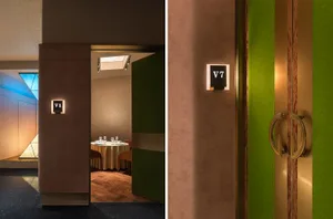 Close-up of a restaurant interior with a green and gold color scheme, featuring a door with a number plate and a chandelier.