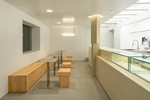 A minimalist restaurant interior with wooden benches and tables.