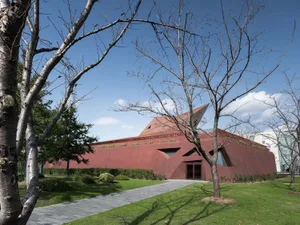 Red metal building with geometric design and green lawn