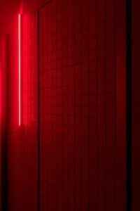 Minimalist red tiled interior design featuring a bright red neon light.