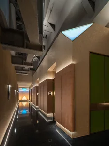 A modern, minimalist corridor with concrete walls and floors, illuminated by soft, ambient lighting.
