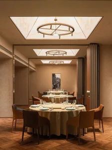 Modern dining room with round tables, chairs, and a chandelier.