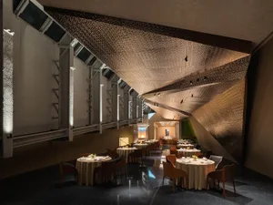 Modern restaurant interior with metal-textured ceiling and tables set for dining.