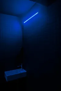A minimalist bathroom with blue lighting and tile walls.