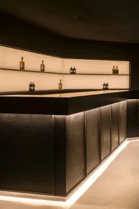 A sleek, modern bar interior with black accents and metallic panels