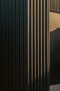 A modern exterior featuring dark metal panels with varied light reflections.