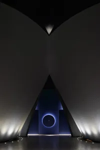 A minimalistic, dark architectural interior with dramatic lighting and geometric shapes.