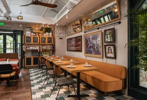 Industrial-style restaurant interior with wooden tables, metal chairs, and tiled floor.
