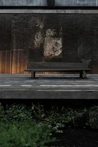 A minimalist park bench made of wood in a parking lot setting.