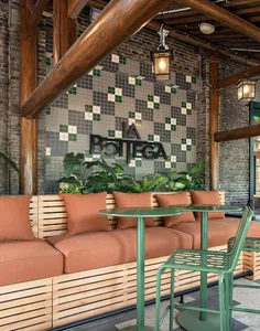 Industrial-style cafe interior with brick walls, tiled mosaic backsplash, wooden seating, and metal furniture.