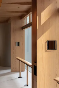 A modern, minimalist lobby interior featuring wooden walls and flooring.