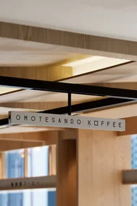 A modern coffee shop interior with a wooden sign that reads 'OMOTESANDO KOFFEE'.