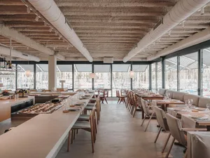 Modern restaurant interior with a marine view and concrete design elements.