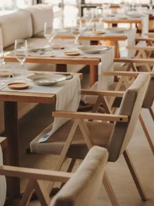 A modern restaurant interior featuring minimalist design with wooden tables and chairs.