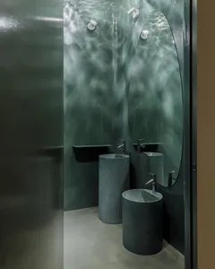 A modern bathroom featuring concrete sinks and glass walls