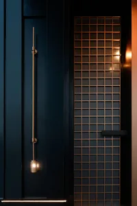 A modern minimalist door with a grid pattern made of metal, illuminated by warm lighting against a dark background.