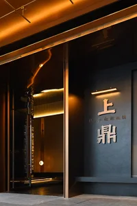 Modern entrance to a restaurant during nighttime with metallic and glass elements