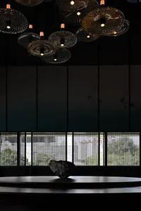 An elegant lobby interior with hanging glass light fixtures and a large stone sculpture on a round table.