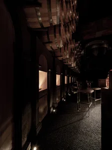 A modern wine bar decorated with wooden barrels, featuring tall stools and ambient lighting.