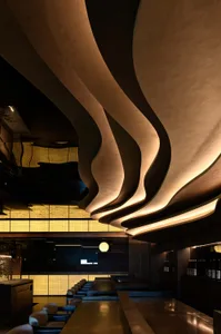 Modern industrial restaurant interior featuring a concrete bar and unique ceiling design.