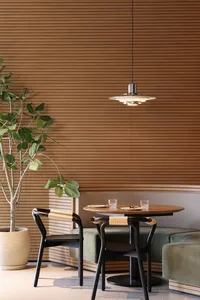 Industrial-style restaurant interior with wooden walls and furniture, green plant, round wooden table, and hanging modern lig