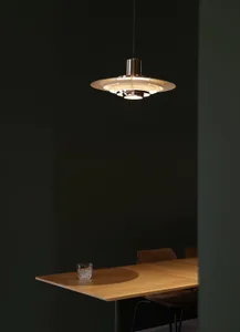 A modern dining room featuring a wooden table with a single glass drink container.