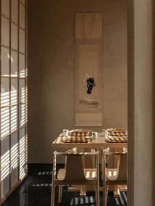 Modern Japanese dining room with wooden furniture, featuring a table, chairs, and traditional artwork.