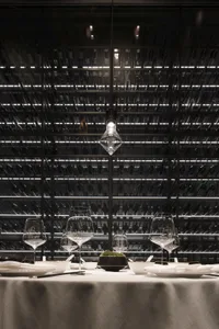 A modern industrial restaurant interior with metal racks, glassware, and minimalist design.