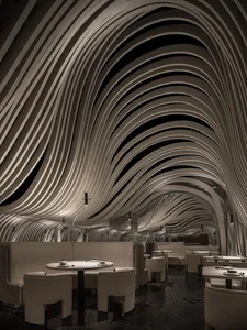 A minimalist white interior with a curved metal roof and illuminated by spotlights.