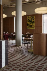 Interior of a modern restaurant with wood walls, metal tables, and glass windows.