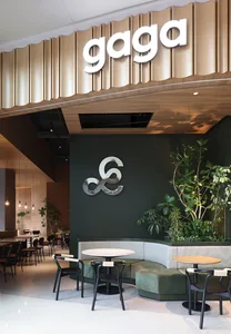 A modern cafe interior featuring metal accents, wood finishes, and green plants.