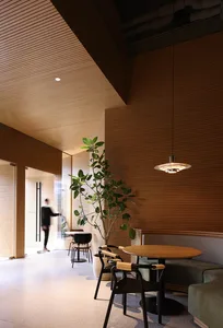 A modern cafe interior with wooden walls and a person walking through the doorway.