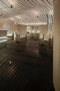 A modern interior space with concrete walls, illuminated by soft, warm lighting.