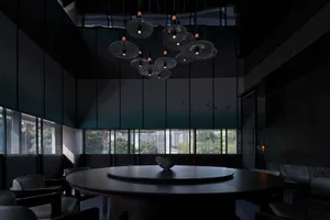 Modern minimalist restaurant dining room with black metal table, chairs, and pendant lights hanging from the ceiling.