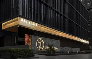 A modern storefront with illuminated signage featuring a metallic cladding design and a marble base.