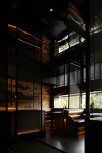 A modern industrial restaurant interior with dark walls, metal railings, and window lighting creating a warm atmosphere.