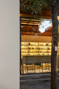 Modern bookstore entrance with glass display case filled with books and illuminated by warm lights.