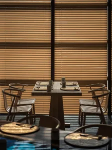 A modern restaurant room with wooden furniture and a table setup for dining.