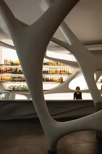 A modern bar interior with a concrete ceiling and wavy, organic architectural design.