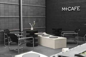 A modern cafe with concrete seating and tables, featuring a minimalist design.